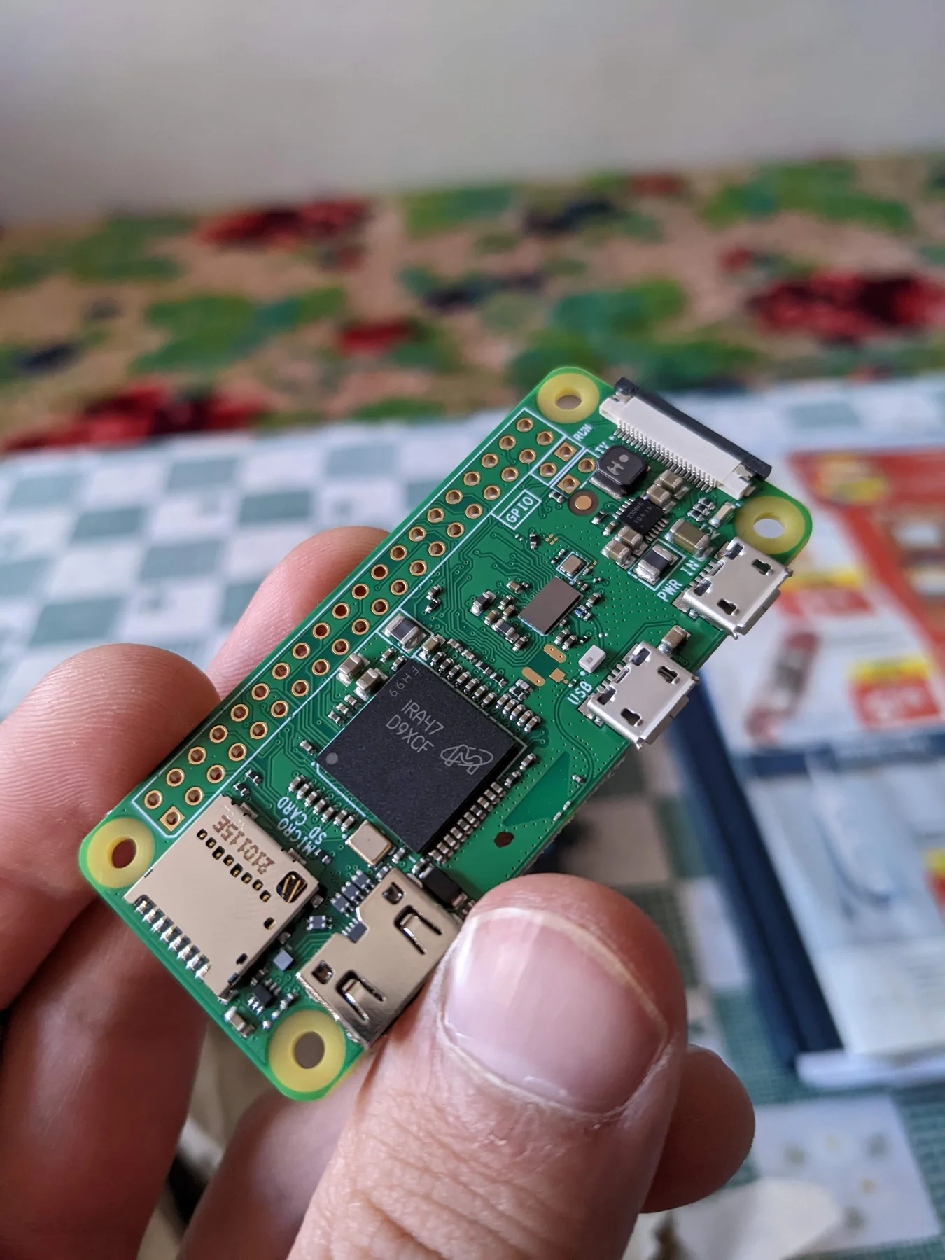Headerless Raspberry Pi Zero held in one hand with its components facing up