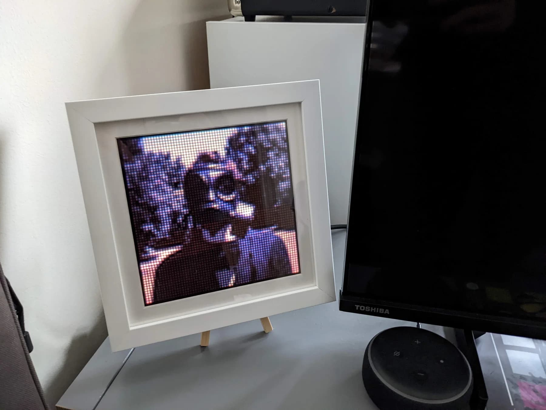 Framed display on a stand showing a pixelated photograph